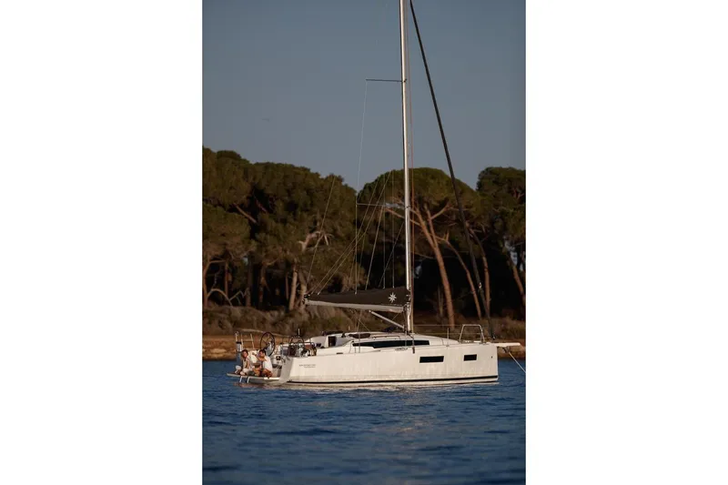 Slide: The Image of 2026 Jeanneau Sun Odyssey 350 sailboat on calm water near a forested shoreline. - 6