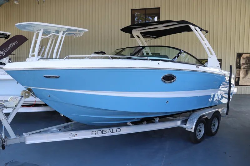 The Image of 2026 Chaparral 250 OSX boat in blue on a Robalo trailer, parked indoors. - 0