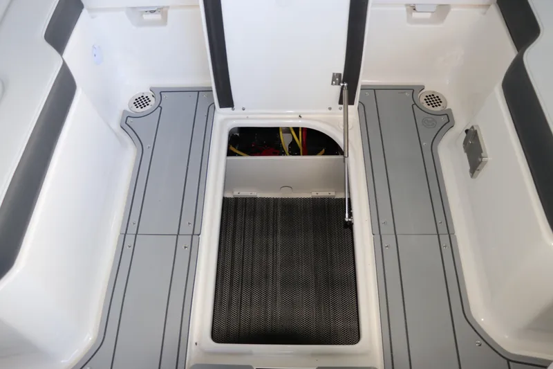 Slide: The Image of 2026 Chaparral 250 OSX boat interior with open storage compartment and gray flooring. - 23