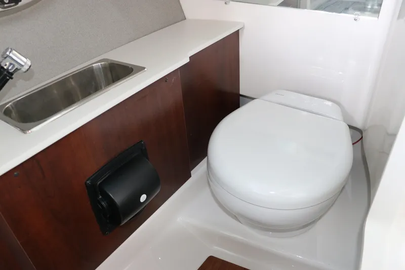 Slide: The Image of 2026 Chaparral 250 OSX boat interior with sink and toilet in compact bathroom. - 49