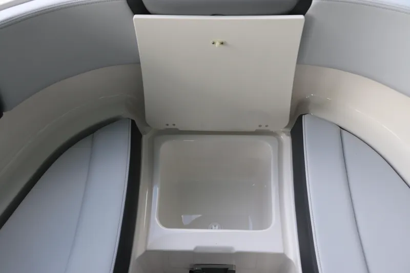 Slide: The Image of 2026 Chaparral 250 OSX boat storage compartment with open lid, showcasing interior space. - 59