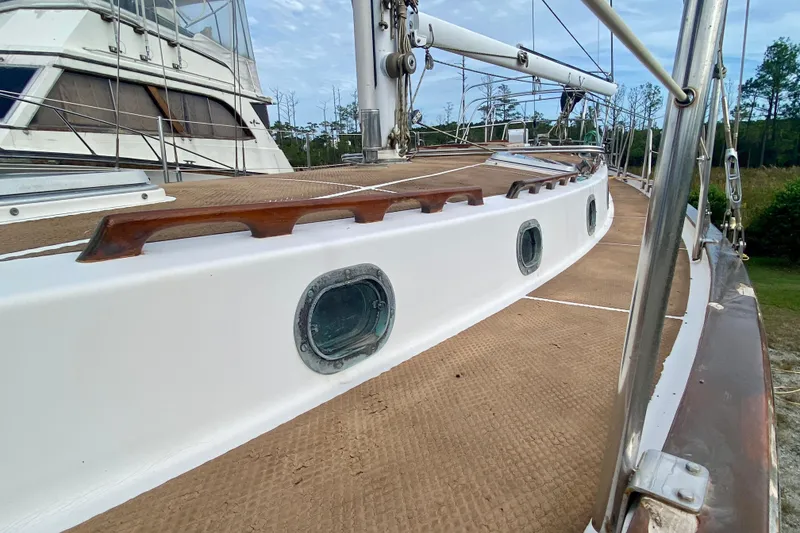 Slide: The Image of 1983 Liberty 38 Cutter sailboat deck with portholes and wooden handrails. - 12