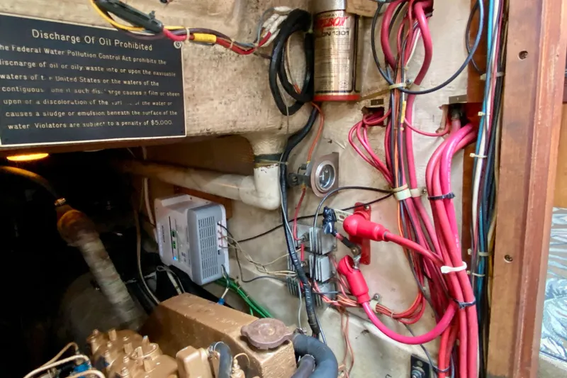 Slide: The Image of Engine compartment of 1983 Liberty 38 Cutter with wiring and oil discharge warning sign. - 29