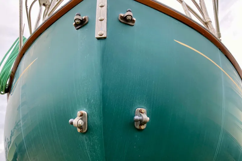 Slide: The Image of Bow of 1983 Liberty 38 Cutter sailboat with green hull and metal fittings. - 38