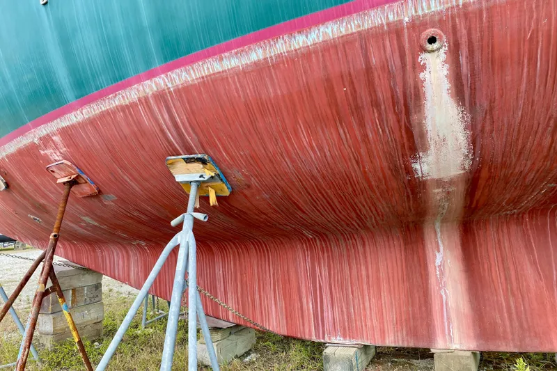 Slide: The Image of 1983 Liberty 38 Cutter sailboat hull on stands, showing red and green paint. - 40