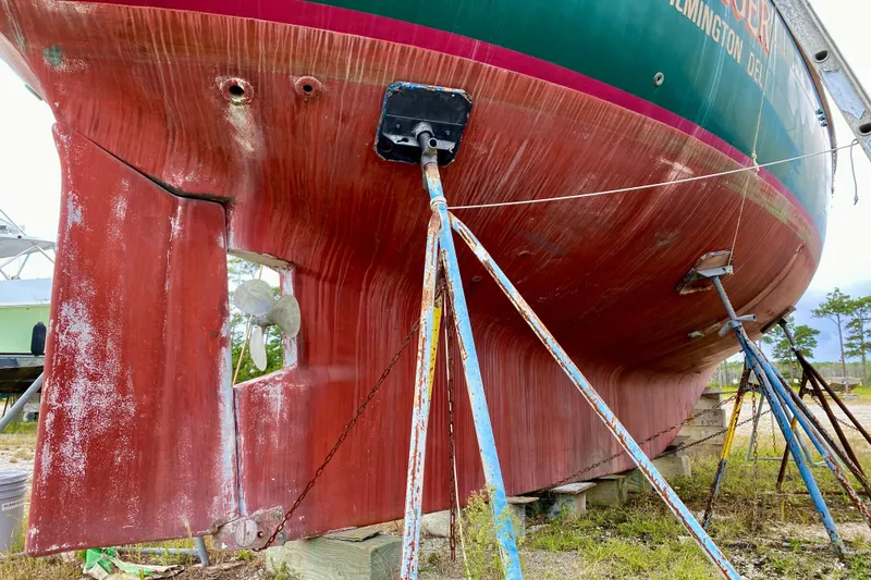 Slide: The Image of 1983 Liberty 38 Cutter sailboat on stands, showing weathered red hull and propeller. - 42