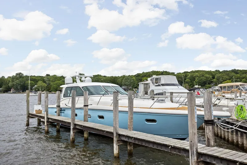 Slide: The Image of 2003 Tiara Yachts 5200 Sovran docked at a marina under a partly cloudy sky. - 4