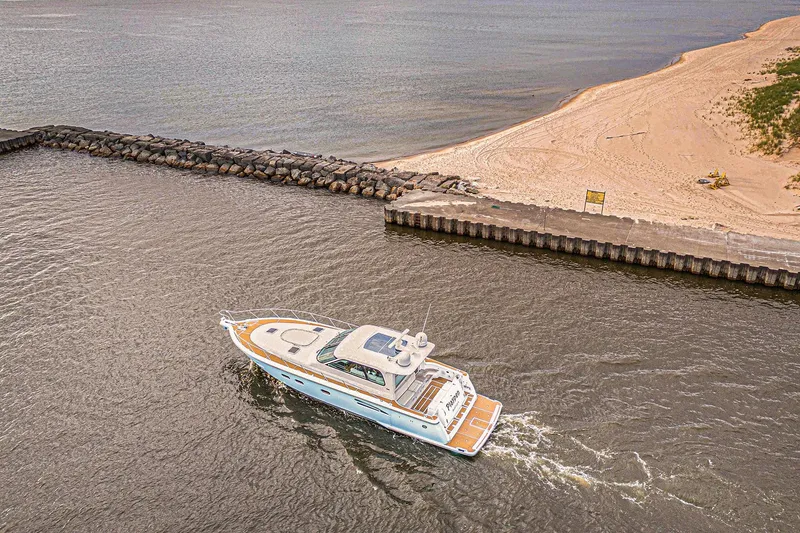 Slide: The Image of 2003 Tiara Yachts 5200 Sovran cruising near a sandy beach and rocky shoreline. - 5