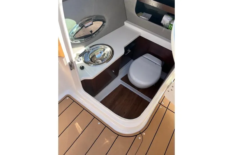 Slide: The Image of 2021 Chaparral 307 SSX boat bathroom with sink and toilet, featuring wood flooring. - 10