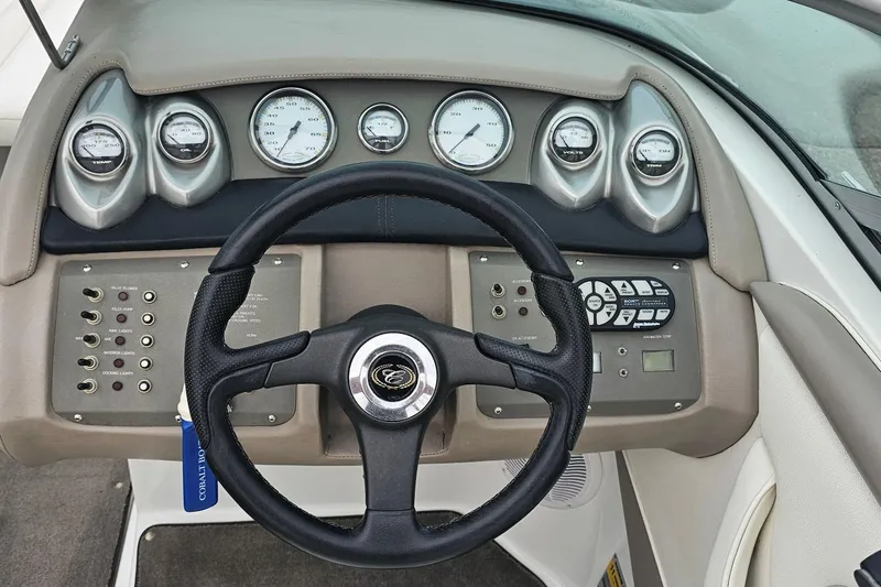Slide: The Image of Steering wheel and dashboard of a 2003 Cobalt 220 boat with gauges and controls. - 11
