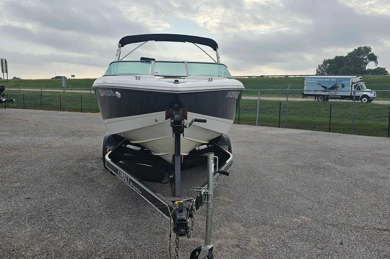 Slide: The Image of 2003 Cobalt 220 boat on trailer, parked outdoors under cloudy sky. - 2