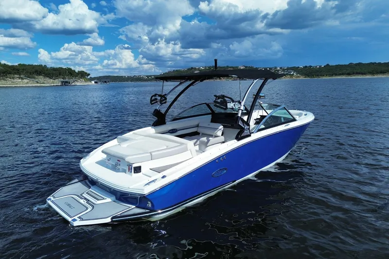 Slide: The Image of 2018 Cobalt CS23 Surf boat on a scenic lake under a cloudy sky. - 1