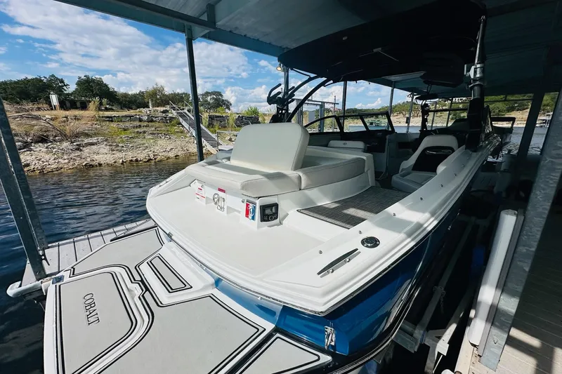 Slide: The Image of 2018 Cobalt CS23 Surf boat docked, featuring sleek design and spacious seating. - 11