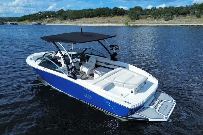 Slide: The Image of 2018 Cobalt CS23 Surf boat on a lake with scenic shoreline. - 2