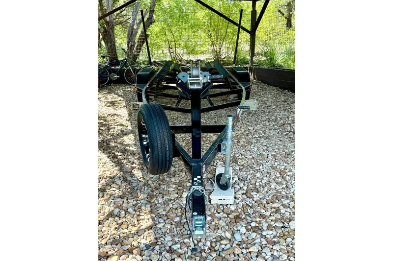 Slide: The Image of Trailer for 2018 Cobalt CS23 Surf boat on gravel, surrounded by trees. - 28