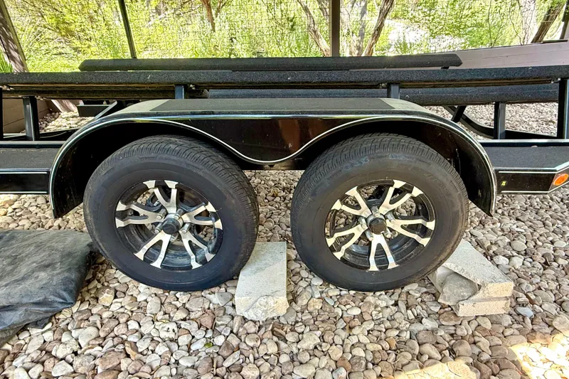 Slide: The Image of Trailer wheels of a 2018 Cobalt CS23 Surf boat on rocky ground. - 31