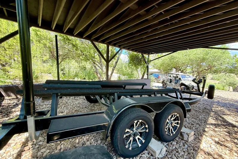 Slide: The Image of Trailer for 2018 Cobalt CS23 Surf boat parked under a wooden shelter. - 33
