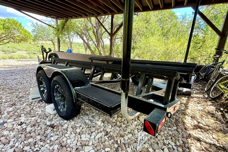 Slide: The Image of 2018 Cobalt CS23 Surf boat trailer parked on gravel under a wooden shelter. - 34