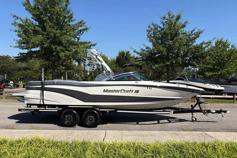 The Image of 2019 MasterCraft boat on trailer, parked outdoors with trees in background. - 0