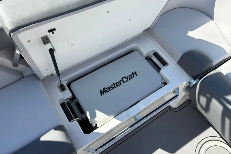 Slide: The Image of 2019 MasterCraft boat storage compartment with open lid and visible branding. - 11