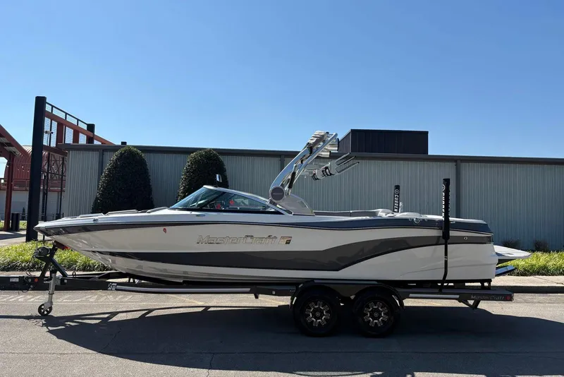 Slide: The Image of 2019 MasterCraft boat on trailer, parked outdoors under clear blue sky. - 3