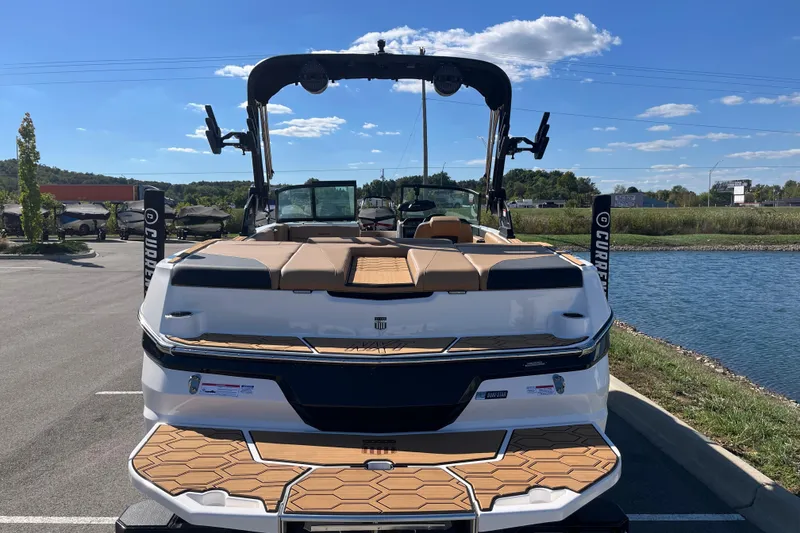 Slide: The Image of 2025 MasterCraft NXT23 boat parked by a lake under a clear blue sky. - 5