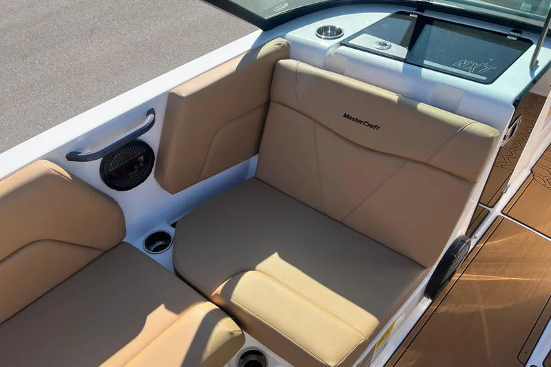 Slide: The Image of 2025 MasterCraft NXT23 boat interior with tan seating and cup holders. - 8