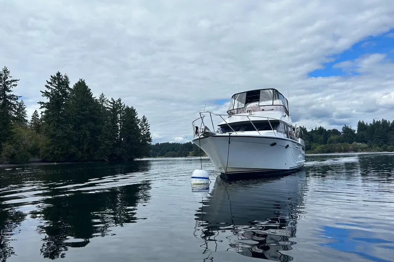 Slide: The Image of 1988 Ocean Alexander 42' yacht anchored on calm water, surrounded by lush trees. - 3