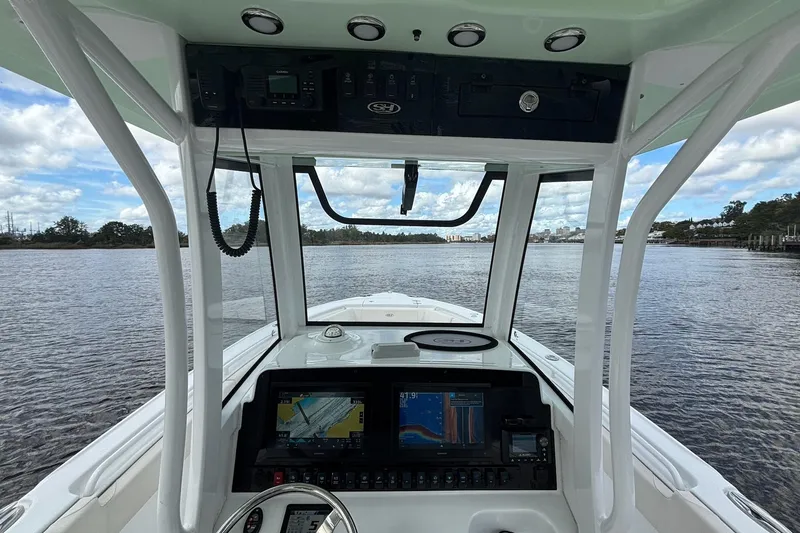 Slide: The Image of 2024 Sea Hunt Ultra 255 SE helm with dual displays and steering wheel on water. - 10