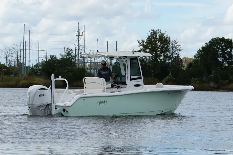 Slide: The Image of 2024 Sea Hunt Ultra 255 SE boat cruising on a calm lake with trees in the background. - 17
