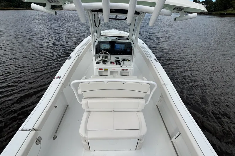Slide: The Image of 2024 Sea Hunt Ultra 255 SE boat interior with helm and seating on calm water. - 7