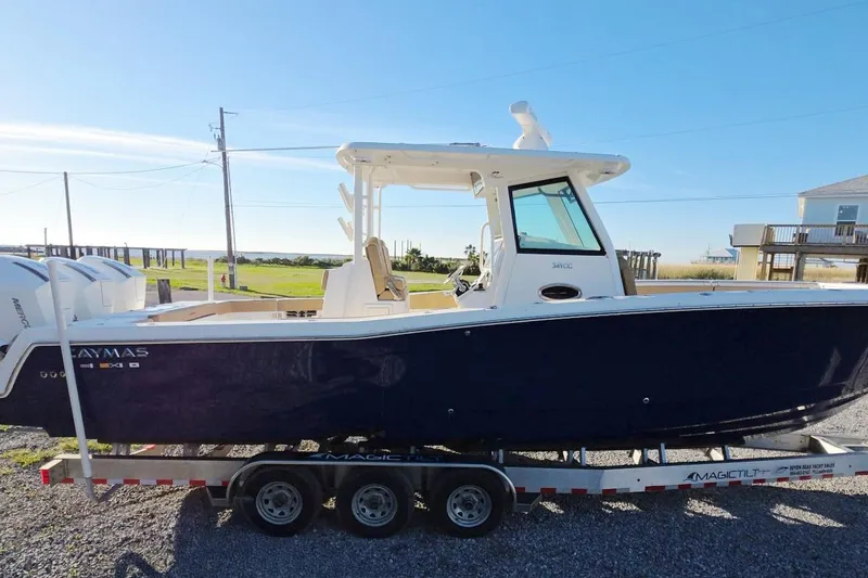 The Image of 2023 Caymas 341 CC boat on trailer, side view, outdoors under clear blue sky. - 1