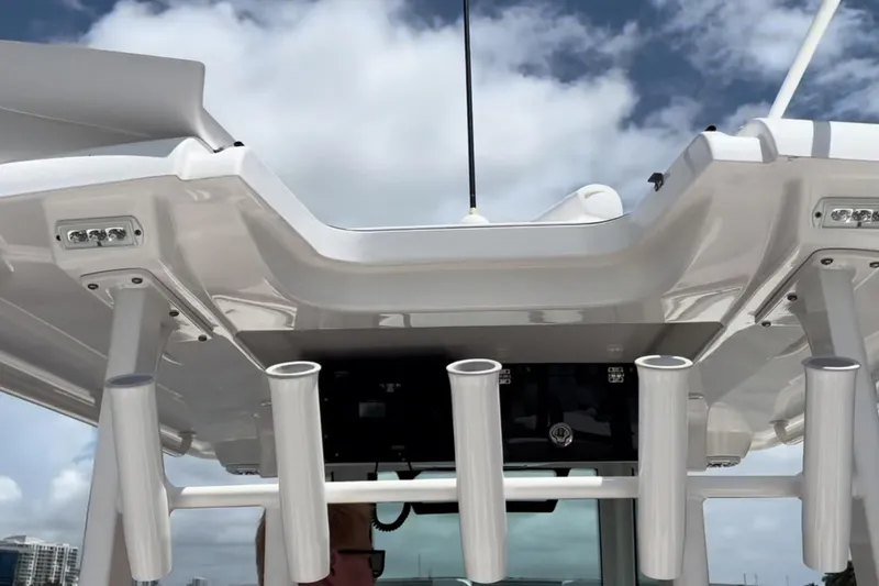 Slide: The Image of 2023 Caymas 341 CC boat roof with rod holders against a cloudy sky. - 18