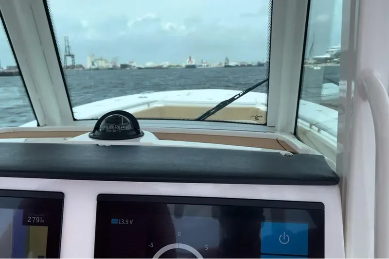 Slide: The Image of 2023 Caymas 341 CC boat dashboard with compass and digital displays on open water. - 23
