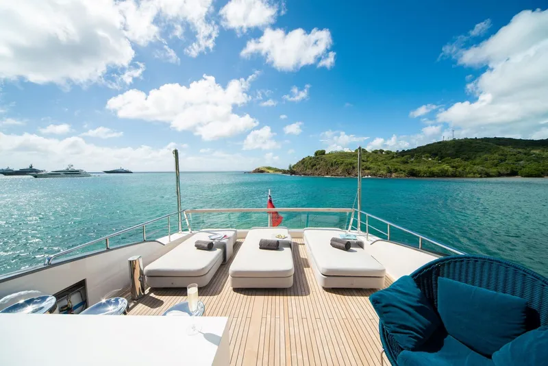 Slide: The Image of Luxurious Sanlorenzo SL86 yacht deck with sun loungers, overlooking serene blue waters and lush island. - 24