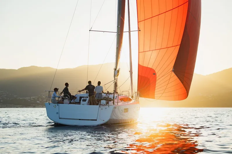 Slide: The Image of 2026 Jeanneau Sun Odyssey 415 sailing at sunset with vibrant red sails. - 10