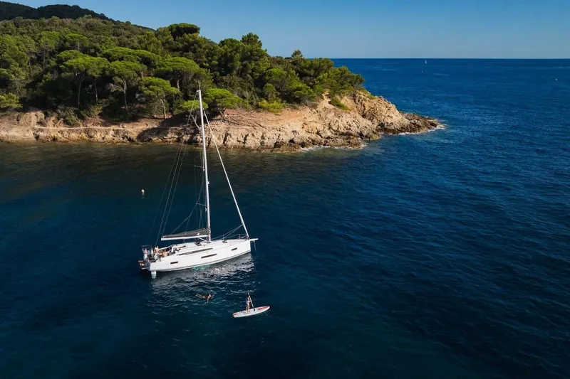 Slide: The Image of 2026 Jeanneau Sun Odyssey 415 sailing near a scenic rocky coastline with lush greenery. - 7