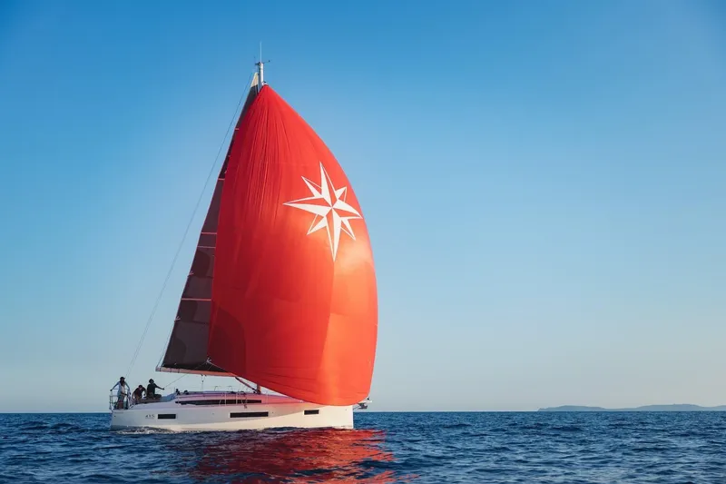 Slide: The Image of 2026 Jeanneau Sun Odyssey 415 sailing with vibrant red spinnaker on open sea. - 9