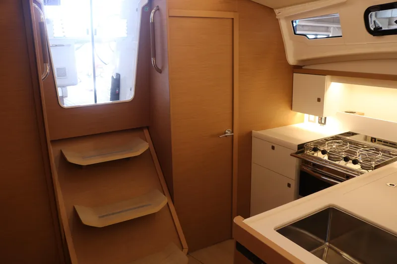 Slide: The Image of Interior of 2026 Jeanneau Sun Odyssey 415 yacht, featuring modern kitchen and wooden stairs. - 27
