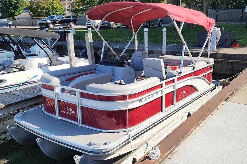 The Image of 2022 Bennington 198SL pontoon boat with red canopy docked at marina. - 1