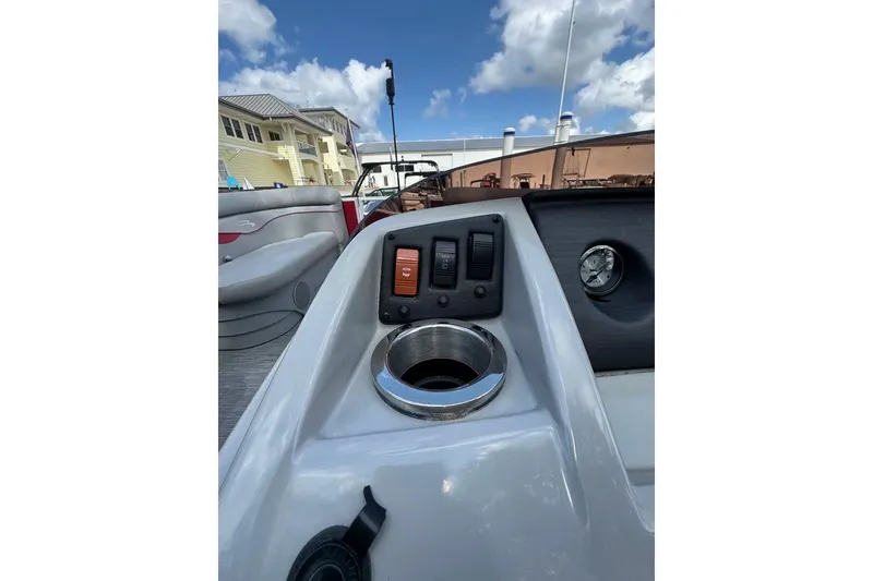 Slide: The Image of 2022 Bennington 198SL boat dashboard with switches and cup holder under a blue sky. - 10
