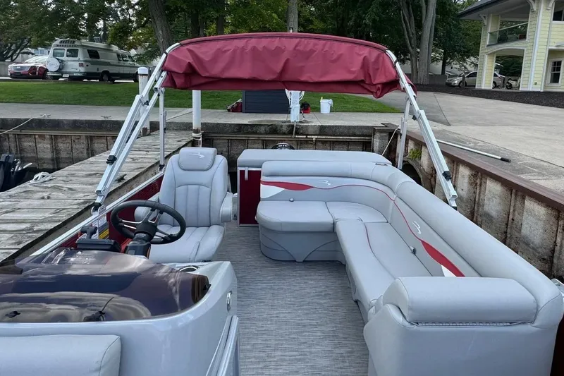 Slide: The Image of 2022 Bennington 198SL pontoon boat with red canopy and gray seating at dock. - 11