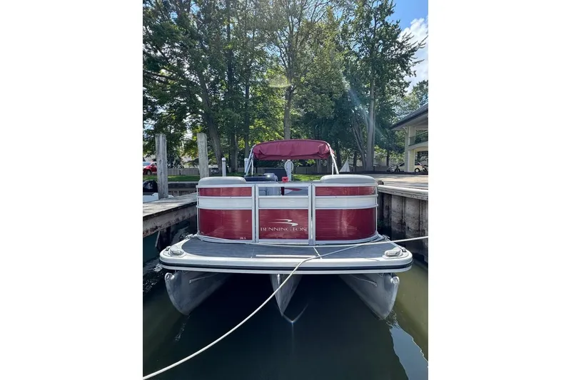 Slide: The Image of 2022 Bennington 198SL pontoon boat docked, featuring red and silver design. - 2