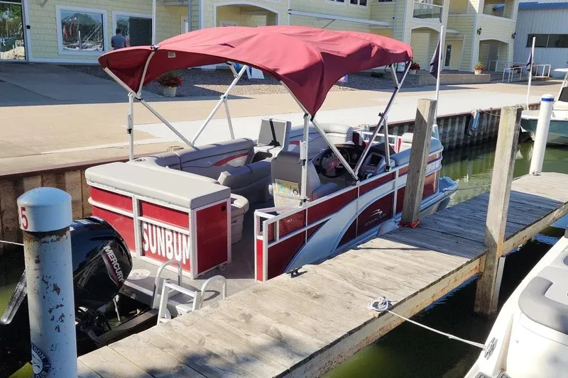 Slide: The Image of 2022 Bennington 198SL pontoon boat docked with red canopy and "SUNBUM" sign. - 26