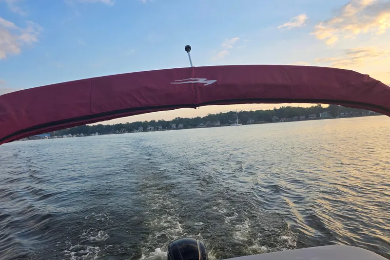 Slide: The Image of 2022 Bennington 198SL boat cruising on a serene lake at sunset. - 34