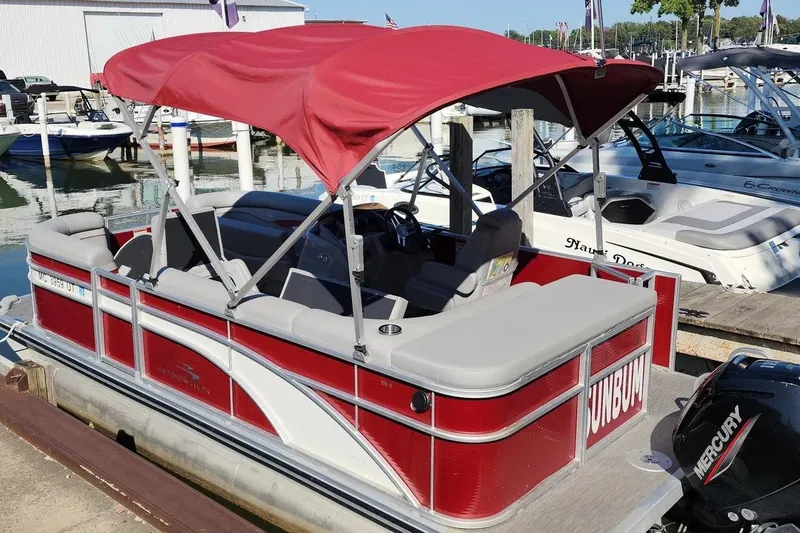 Slide: The Image of 2022 Bennington 198SL pontoon boat with red canopy docked at marina. - 4