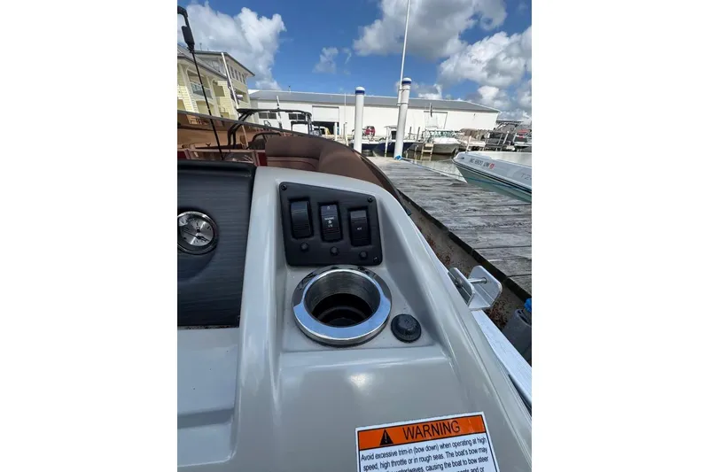 Slide: The Image of 2022 Bennington 198SL boat dashboard with controls and warning label at marina. - 9
