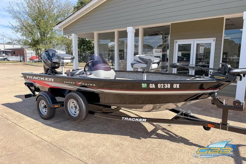 Slide: The Image of 2015 Tracker Super Guide V-16 SC boat on trailer, parked outside a building. - 2