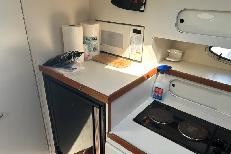 Slide: The Image of 1993 Tiara Yachts 3100 Open galley with stove, microwave, and cleaning supplies. - 17