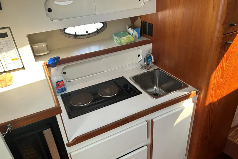 Slide: The Image of 1993 Tiara Yachts 3100 Open galley with stove, sink, and wooden cabinetry. - 18